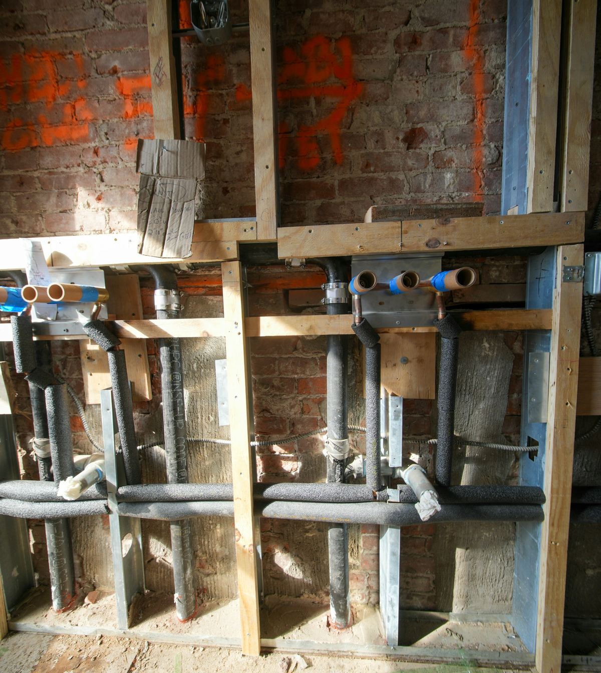 Nieuwe water- en afvoerleidingen in een opengewerkte muur